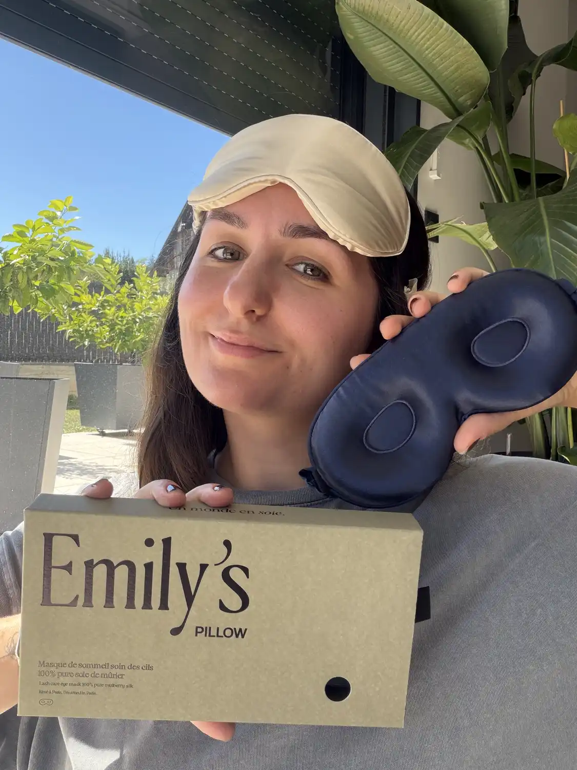 J'ai testé 2 mois le masque pour les cils d'Emily's Pillow : mon avis complet 2 Emilie porte le masque en soie champagne relevé sur le front et tient le masque bleu nuit devant la boîte Emily's Pillow