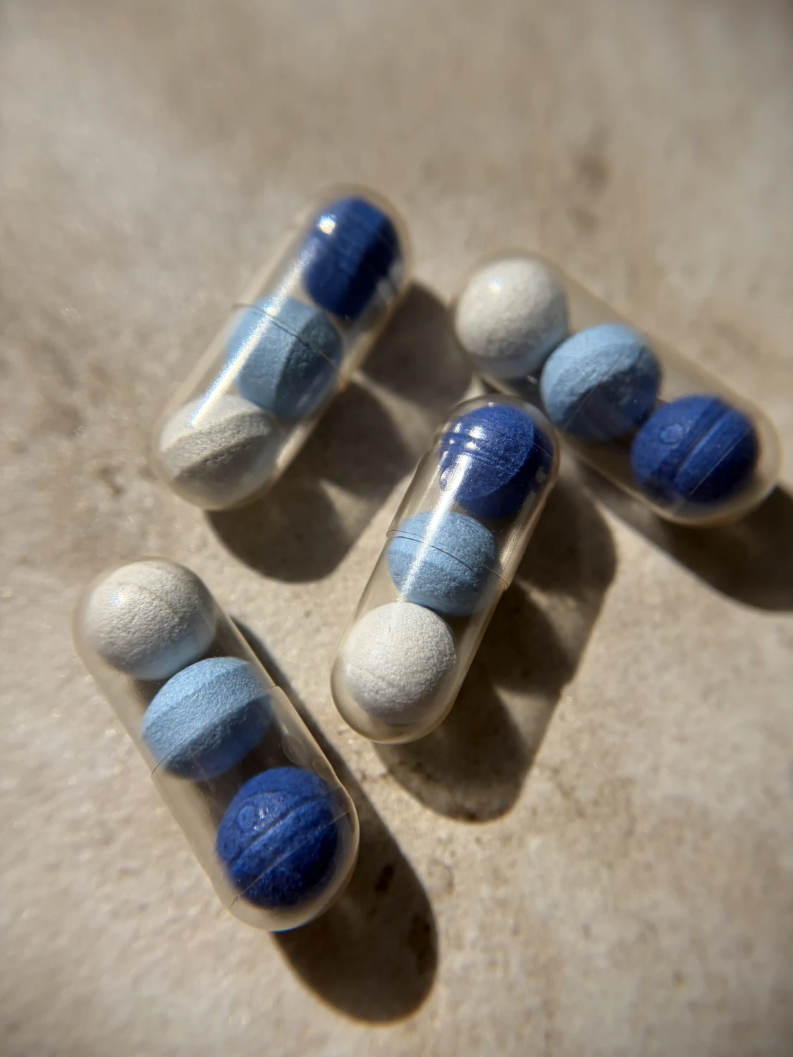 J'ai testé SR-3C de Cuure pour mon sommeil : mon avis complet 8 Plusieurs gélules Cuure SR-3C posées côte à côte, avec leurs trois billes bleu foncé, bleu clair et blanche